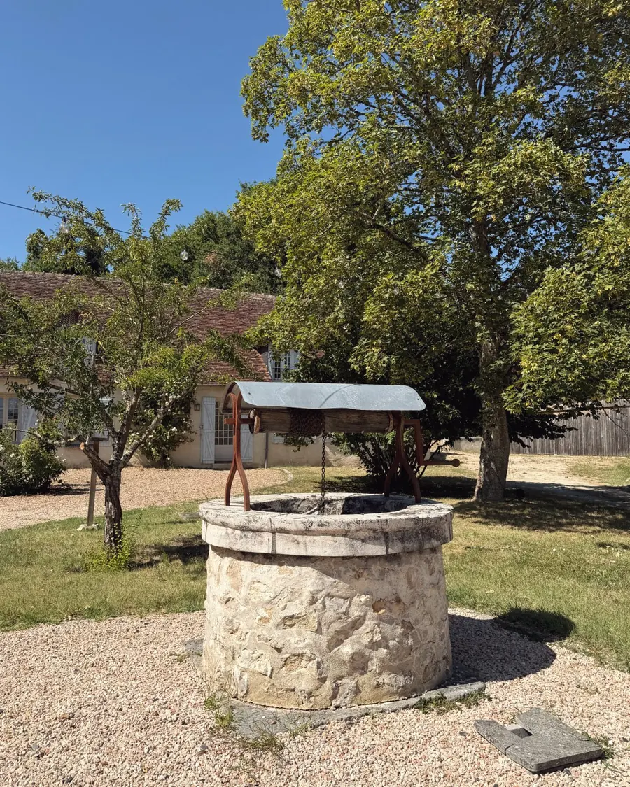 Le puits de pierre au milieu de la cour de gravier