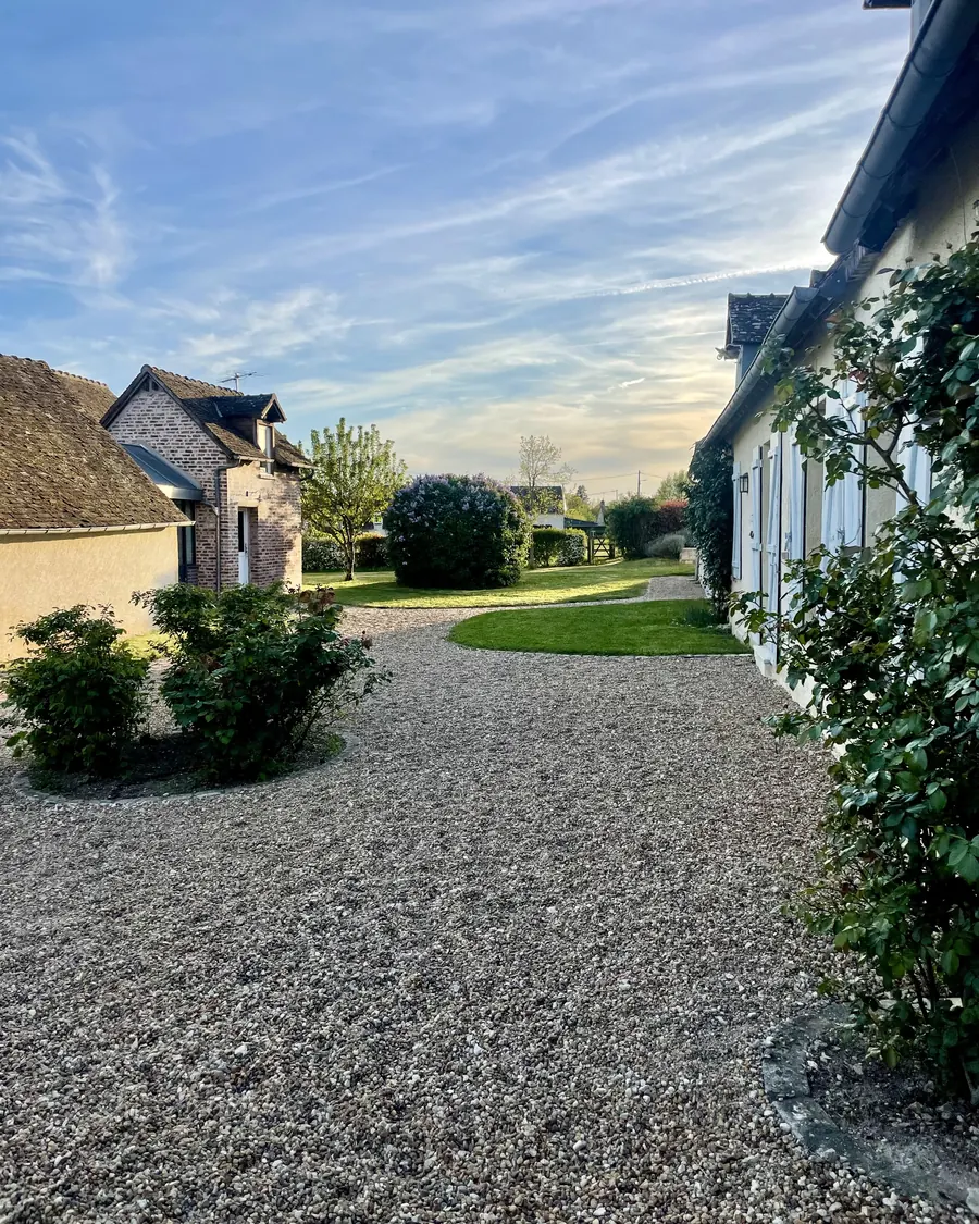 La longue façade de la longère bordée par l'allée de gravier