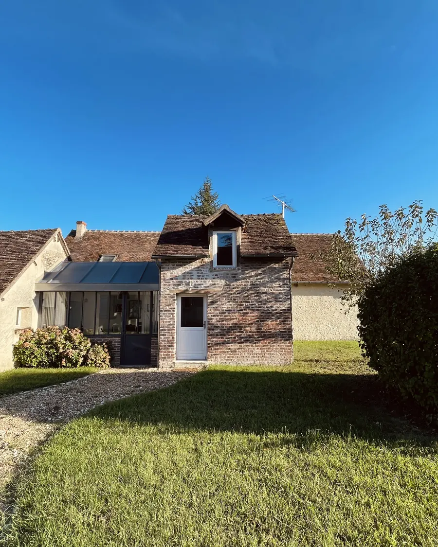 La petite maison de pierre et sa façade vitrée, au bord de la pelouse