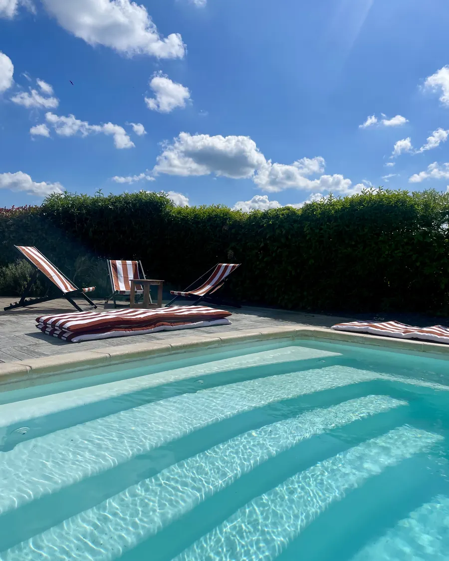 La piscine et ses transats rayés, le long de la haie