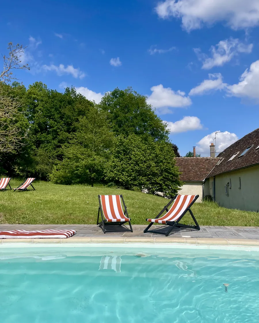 Les transats en bois au bord de la piscine, sous les arbres